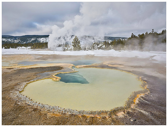 Hot spring and erupting geyser, Winter, Yellowstone NP, Wyoming